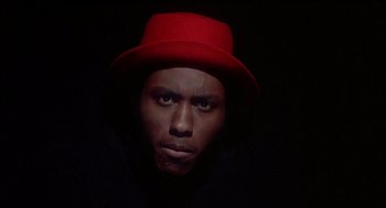 Movie still from “Beat Street” (1984), directed by Stan Lathan – A man wearing a red hat in the dark; Close Up shot, Low angle