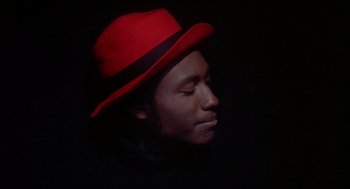 Movie still from “Beat Street” (1984), directed by Stan Lathan – A man wearing a red hat and a black jacket; Close Up shot, Low angle