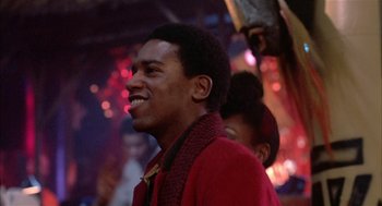 Movie still from “Beat Street” (1984), directed by Stan Lathan – A man in a red coat smiling at a party; Close Up shot, Low angle