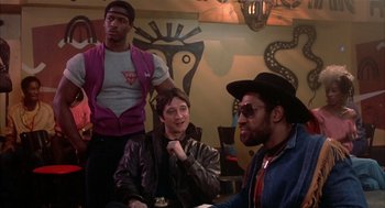 Movie still from “Beat Street” (1984), directed by Stan Lathan – A group of people sitting in a room; Medium shot, Over the shoulder angle