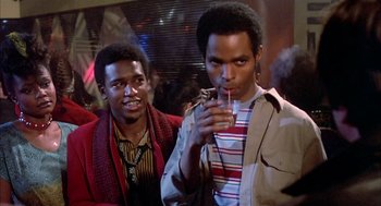 Movie still from “Beat Street” (1984), directed by Stan Lathan – Two young men standing next to each other holding a drink; Medium shot, Low angle
