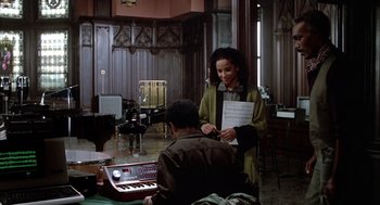 Movie still from “Beat Street” (1984), directed by Stan Lathan – Two people are standing in a room and one person is playing a keyboard; Wide shot, High angle