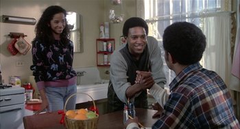 Movie still from “Beat Street” (1984), directed by Stan Lathan – A man sitting at a table with a basket of fruit; Medium shot, Over the shoulder angle