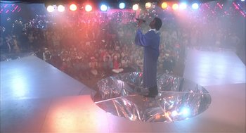 Movie still from “Beat Street” (1984), directed by Stan Lathan – A man is singing on a stage while people watch; Wide shot, High angle