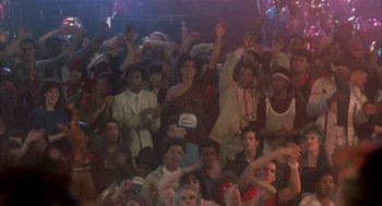 Movie still from “Beat Street” (1984), directed by Stan Lathan – A group of people are gathered together in a room; Wide shot, High angle