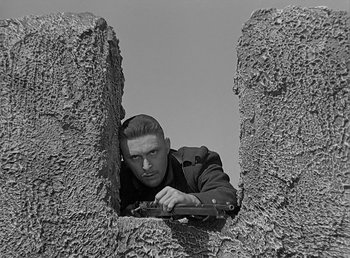 Movie still from “Beau Geste” (1939), directed by William A. Wellman – A black and white photo of a man holding a gun; Close Up shot, Low angle