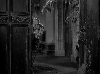 Movie still from “Beau Geste” (1939), directed by William A. Wellman – A black - and - white photo of two masks in a doorway; Medium shot, High angle