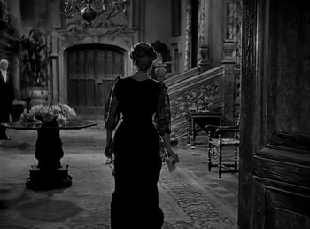 Movie still from “Beau Geste” (1939), directed by William A. Wellman – A woman walking down a hall way in a dress; Wide shot, Over the shoulder angle