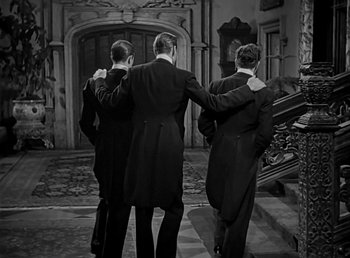 Movie still from “Beau Geste” (1939), directed by William A. Wellman – A group of three men in tuxedos standing next to each other in front of a staircase; Medium shot, High angle