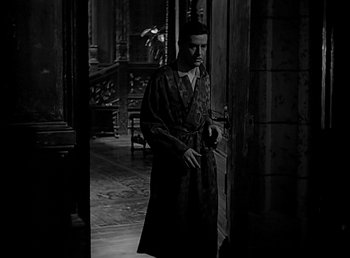 Movie still from “Beau Geste” (1939), directed by William A. Wellman – A black and white photo of a man in a robe standing in front of an open door; Medium shot, High angle