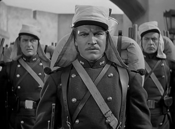 Movie still from “Beau Geste” (1939), directed by William A. Wellman – A group of men in uniforms are standing in a line; Medium shot, Over the shoulder angle