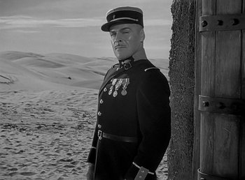 Movie still from “Beau Geste” (1939), directed by William A. Wellman – A man in a military uniform standing next to a tree; Medium shot, Low angle