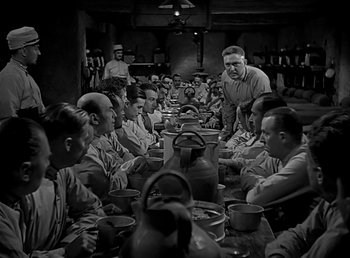 Movie still from “Beau Geste” (1939), directed by William A. Wellman – A group of men sitting at a table with plates of food in front of them; Wide shot, High angle