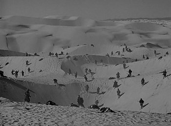 Movie still from “Beau Geste” (1939), directed by William A. Wellman – A black and white photo of people in the sand dunes; Extreme Wide shot, High angle