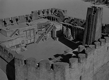 Movie still from “Beau Geste” (1939), directed by William A. Wellman – An aerial view of an old castle with stairs leading up to it; Extreme Wide shot, High angle