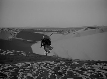 Movie still from “Beau Geste” (1939), directed by William A. Wellman – A man riding a horse through the sand dunes; Extreme Wide shot, High angle