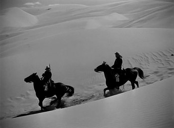 Movie still from “Beau Geste” (1939), directed by William A. Wellman – A couple of men riding on the backs of horses; Wide shot, High angle