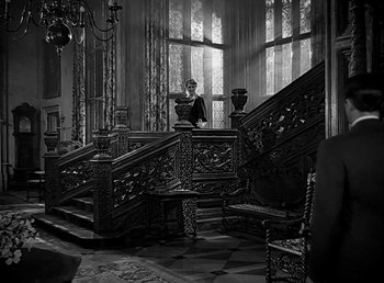 Movie still from “Beau Geste” (1939), directed by William A. Wellman – A man standing in front of a staircase in an ornate room; Wide shot, Over the shoulder angle