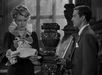 Movie still from “Beau Geste” (1939), directed by William A. Wellman – A man and a woman standing next to each other holding papers; Medium shot, Over the shoulder angle