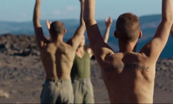Movie still from “Beau Travail” (1999), directed by Claire Denis – A group of men standing on top of a hill; Medium shot, Low angle