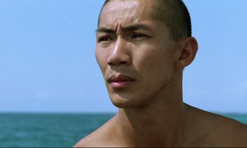 Movie still from “Beau Travail” (1999), directed by Claire Denis – A person with a body of water in the background; Close Up shot, Low angle