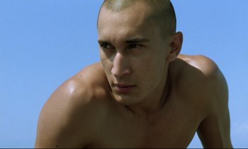 Movie still from “Beau Travail” (1999), directed by Claire Denis – A person with a shaved head; Close Up shot, Low angle