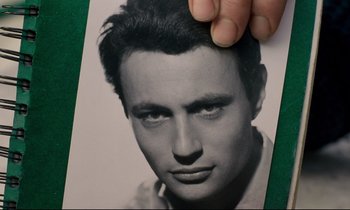 A hand is holding an old photo of a man