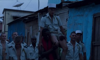 Movie still from “Beau Travail” (1999), directed by Claire Denis – A group of men standing next to each other; Wide shot, Low angle