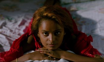Movie still from “Beau Travail” (1999), directed by Claire Denis – A woman laying on the ground with her hands under her chin; Close Up shot, Overhead angle