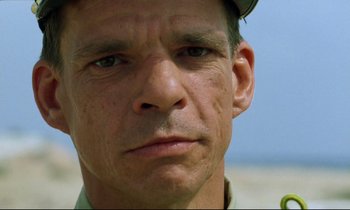 Movie still from “Beau Travail” (1999), directed by Claire Denis – A man's face with a hat on; Close Up shot, Low angle