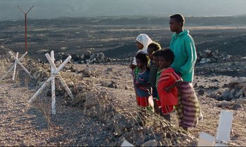 Movie still from “Beau Travail” (1999), directed by Claire Denis – A group of people standing on top of a dirt hill; Extreme Wide shot, Over the shoulder angle
