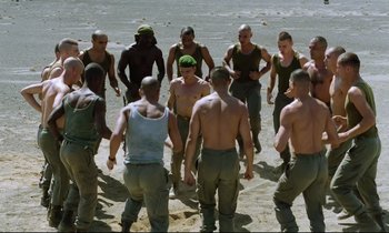 Movie still from “Beau Travail” (1999), directed by Claire Denis – A group of men standing on top of a sandy beach; Wide shot, High angle