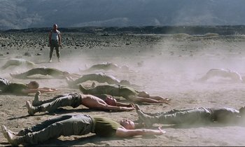 Movie still from “Beau Travail” (1999), directed by Claire Denis – A group of people laying in the sand on the beach; Wide shot, Low angle