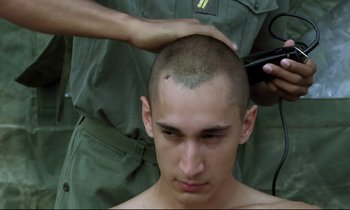 Movie still from “Beau Travail” (1999), directed by Claire Denis – A man getting his head shaved by another man; Close Up shot, Over the shoulder angle