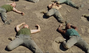 Movie still from “Beau Travail” (1999), directed by Claire Denis – A group of people laying on the ground; Wide shot, Overhead angle