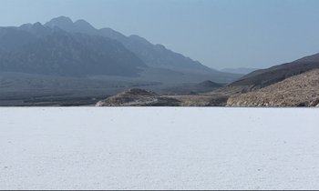 Movie still from “Beau Travail” (1999), directed by Claire Denis – A view of a desert with mountains in the background; Extreme Wide shot, High angle