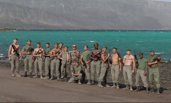 Movie still from “Beau Travail” (1999), directed by Claire Denis – A group of men standing next to each other on a beach; Wide shot, High angle