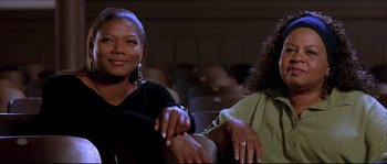 Movie still from “Beauty Shop” (2005), directed by Bille Woodruff – Two women are sitting in a theater and smiling; Close Up shot, Low angle