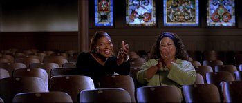 Movie still from “Beauty Shop” (2005), directed by Bille Woodruff – Two women are sitting in a theater clapping and smiling; Medium shot, Low angle