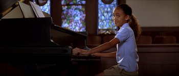 Movie still from “Beauty Shop” (2005), directed by Bille Woodruff – A girl is playing the piano in front of a stained glass window; Medium shot, High angle