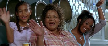 Movie still from “Beauty Shop” (2005), directed by Bille Woodruff – A woman waving at the camera while sitting in a chair; Close Up shot, Over the shoulder angle