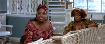 Movie still from “Beauty Shop” (2005), directed by Bille Woodruff – A woman sitting on top of a chair next to another woman; Medium shot, Over the shoulder angle