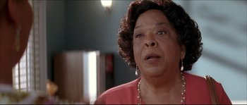 Movie still from “Beauty Shop” (2005), directed by Bille Woodruff – An older woman wearing a pink shirt and a pearl necklace; Close Up shot, Low angle