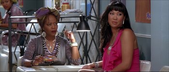 Movie still from “Beauty Shop” (2005), directed by Bille Woodruff – A couple of women sitting at a dinner table; Medium shot, Over the shoulder angle