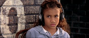 Movie still from “Beauty Shop” (2005), directed by Bille Woodruff – A young girl wearing headphones while sitting against a brick wall; Close Up shot, High angle