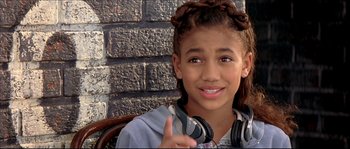 Movie still from “Beauty Shop” (2005), directed by Bille Woodruff – A young girl wearing headphones giving the peace sign; Close Up shot, High angle