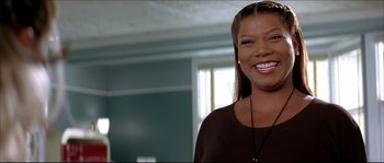 Movie still from “Beauty Shop” (2005), directed by Bille Woodruff – A woman smiling for the camera in a living room; Close Up shot, Low angle