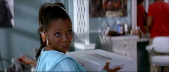 Movie still from “Beauty Shop” (2005), directed by Bille Woodruff – A woman holding a box in a room; Close Up shot, Over the shoulder angle