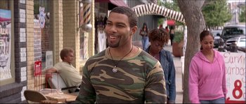 Movie still from “Beauty Shop” (2005), directed by Bille Woodruff – A man in a camouflage shirt smiling for the camera; Medium shot, High angle