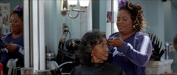 Movie still from “Beauty Shop” (2005), directed by Bille Woodruff – An older woman getting her hair done by a stylist; Medium shot, Over the shoulder angle